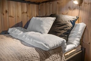 A wooden cabin-style room with a bed, pillows, and a blanket. - Trysil Ski-in/out Apt Sauna (Trysil)
