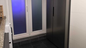 En smal hall med en vit dörr och ett svart kylskåp.