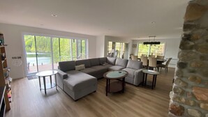 Ein geräumiges Wohnzimmer mit einem großen Ecksofa, zwei runden Couchtischen und einer Wand mit Steinverkleidung.