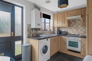 Une cuisine moderne équipée d’un lave-linge, d’un four et d’une cuisinière à gaz.
