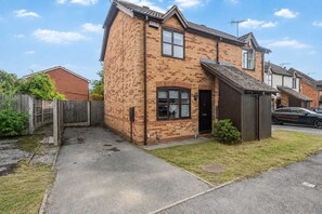 En tvåvånings bostadsbyggnad med en fasad av tegel, en ytterdörr och ett litet garage som är sammanbyggt med huset.