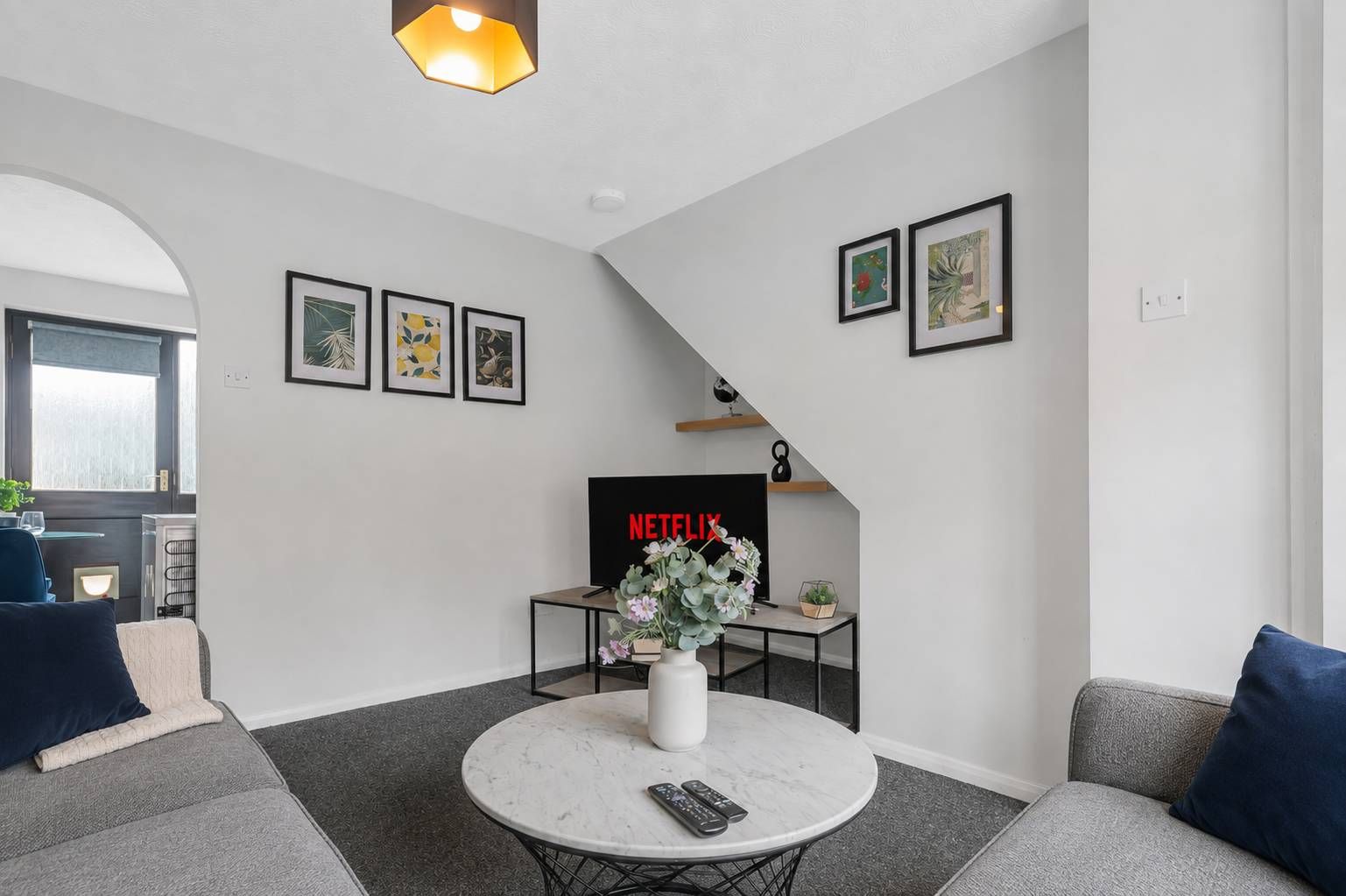 A modern living room with a sofa, a coffee table, a TV, and framed artwork on the wall.