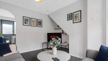 A modern living room with a sofa, a coffee table, a TV, and framed artwork on the wall.