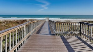 Una passerella di legno che conduce a una spiaggia sotto un cielo azzurro limpido.