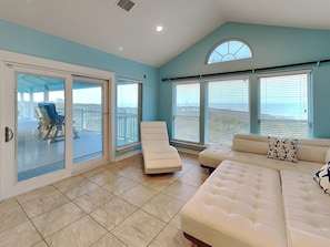 A spacious living area with a large sliding glass door leading to a balcony, a white sofa, and a view of the ocean. - Executive Beach Paradise (Port Aransas)