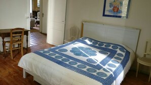 A bedroom with a bed, a chair, a desk, and a painting on the wall.