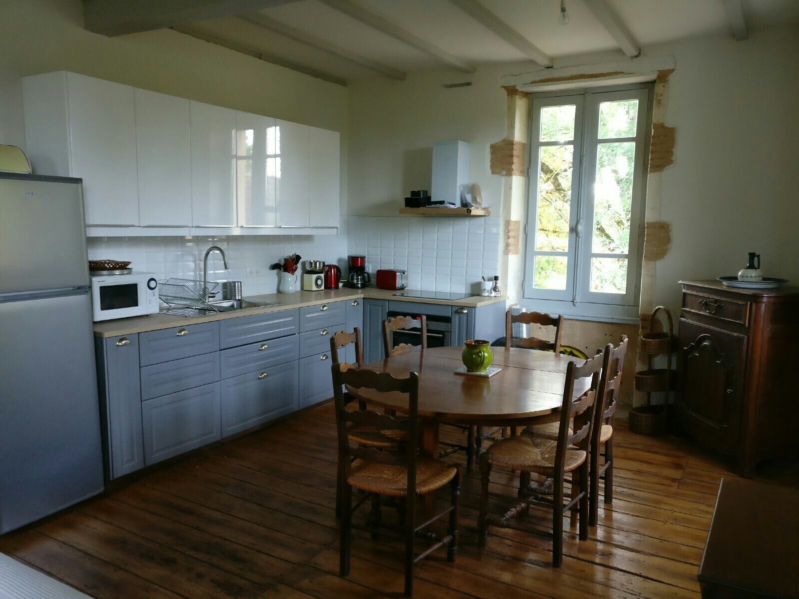 A kitchen with white cabinets, a wooden dining table, and chairs.