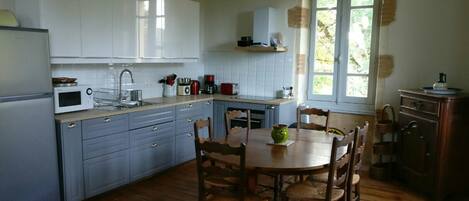 A kitchen with white cabinets, a wooden dining table, and chairs.
