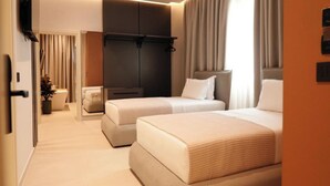A modern hotel room with two beds, a flat-screen TV, a wardrobe, and a potted plant. - Hotel Natica (Ksamil)