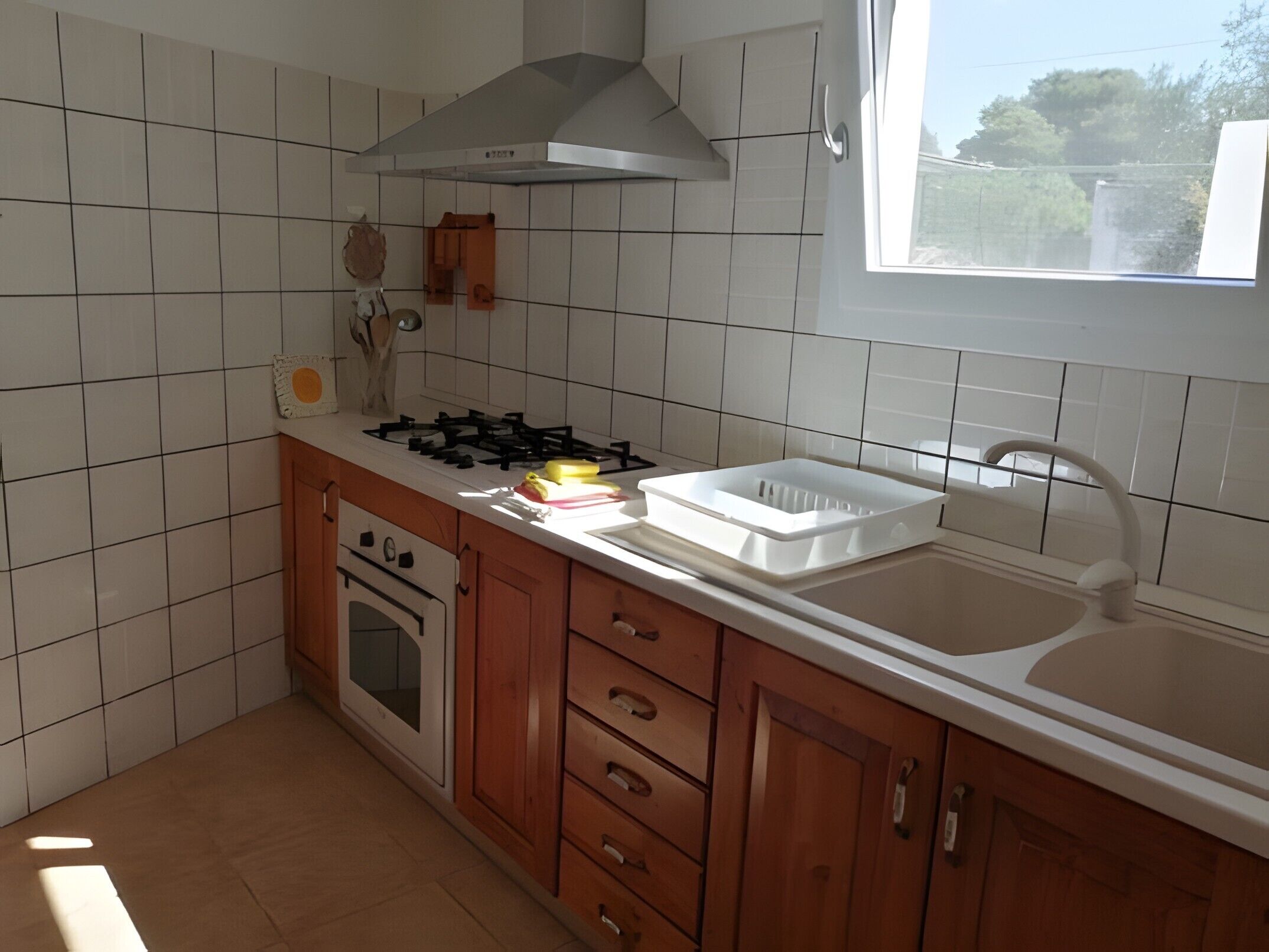 Een koelkast, een oven, een kookplaat, kookgerei, borden en bestek