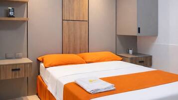 Une chambre moderne avec un grand lit, une literie orange, une tête de lit en bois et des étagères intégrées.