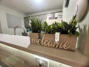 A kitchen with a wooden welcome sign, a sink, and a countertop. - Seaside Hideaway- loaded with resort amenities! (Myrtle Beach)