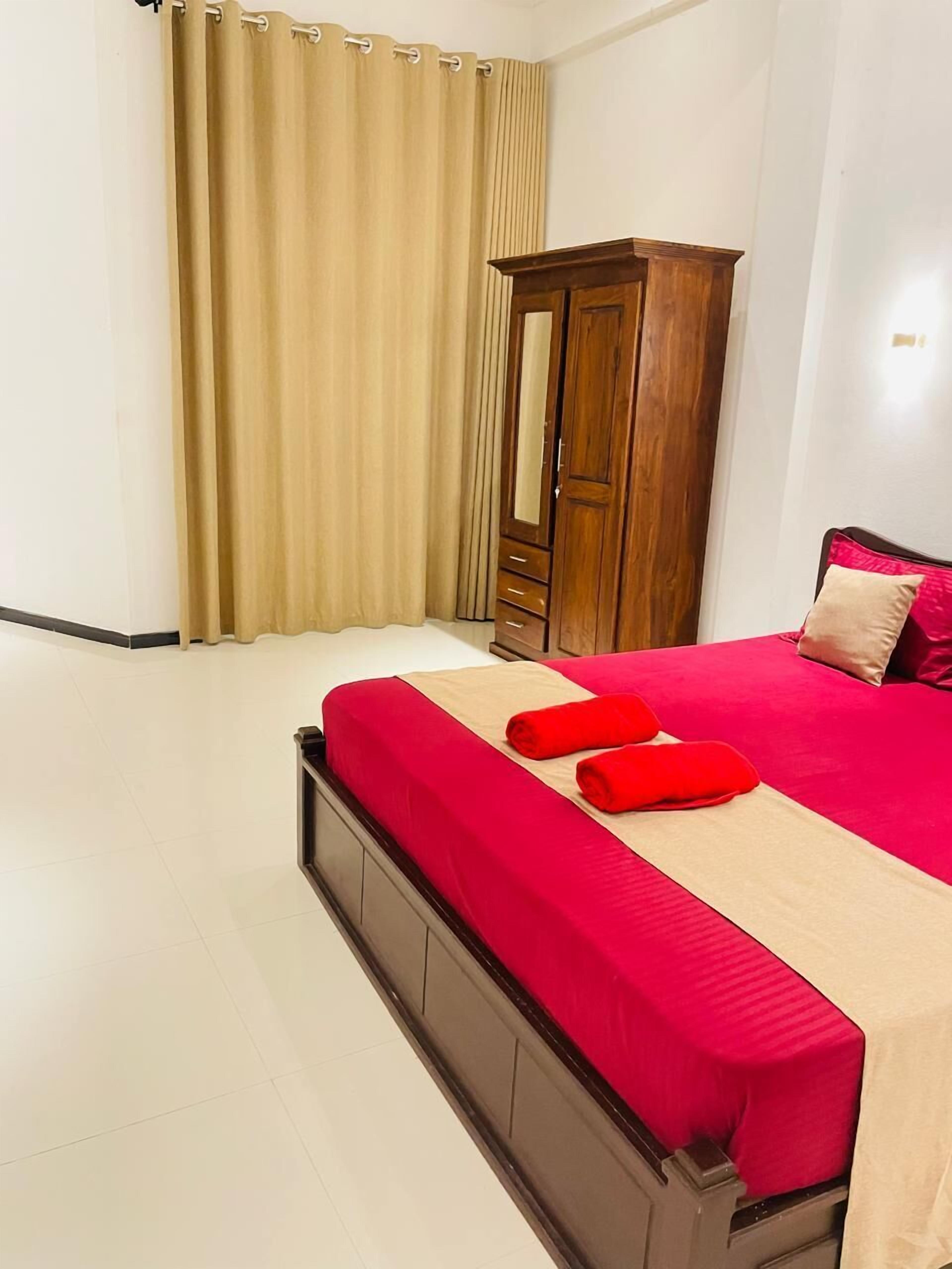 A bedroom with a bed, a wooden wardrobe, and a curtain.