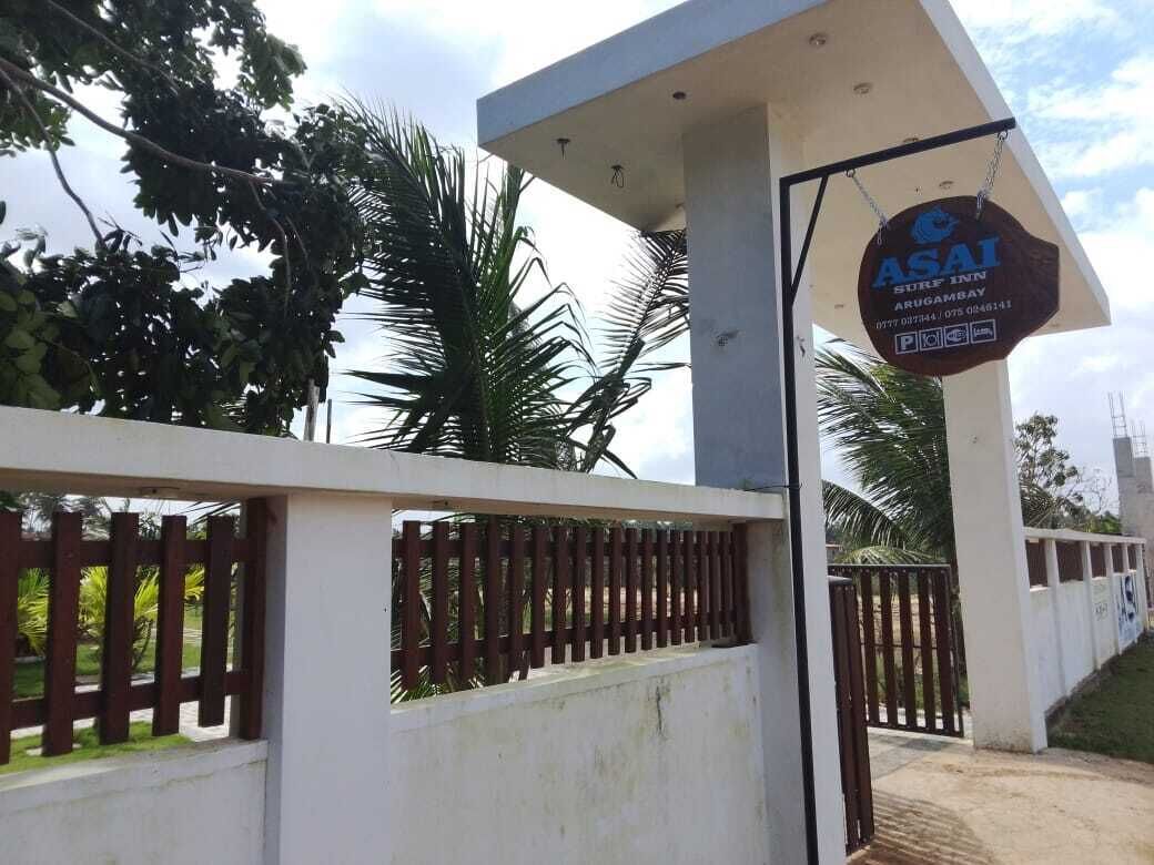 Une entrée fermée par un portail, agrémentée d’une enseigne indiquant « ASAI Surf Inn », et présentant un design moderne avec un pilier en béton et un portail en métal.