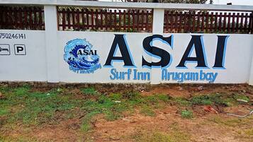 Paredes com o logotipo e nome ASAI Surf Inn, indicando um alojamento à beira-mar.