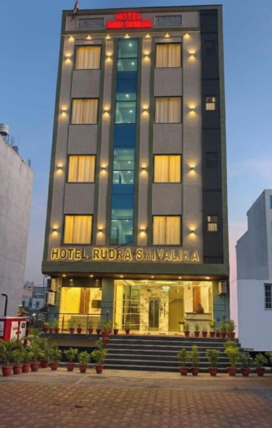 A multi-story hotel building with a prominent entrance and a sign reading 'HOTEL RUDRA SHIVALIKA'.