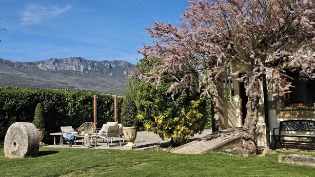 Un jardín con asientos al aire libre, una estructura de piedra y vistas a montañas.