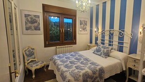 Un dormitorio con cama, una silla, cómoda y radiador.