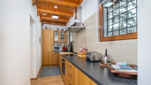 Una cocina con armarios de madera, encimera negra, ventana y vistas a árboles.