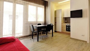 Un apartamento moderno con comedor, cocina y televisor montado en la pared.