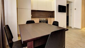 Una cocina moderna con armarios blancos, encimera de madera y horno empotrado.