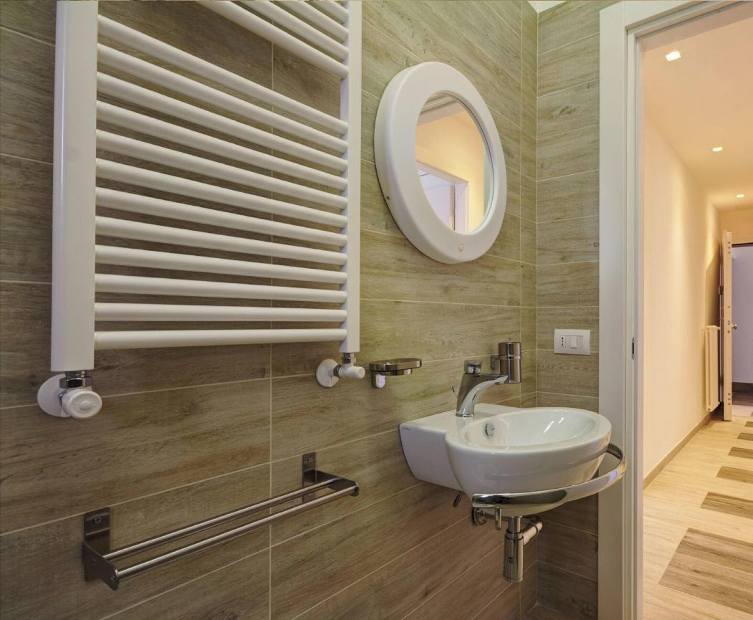 Un baño moderno con lavamanos integrado, un perchero y un radiador de pared.