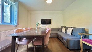 En moderne stue med spisebord, sofa og fjernsyn.