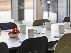 A conference table with white mugs, a bowl of red grapes, and playing cards. - 5 Star Holiday Home in Bogense (Bogense)