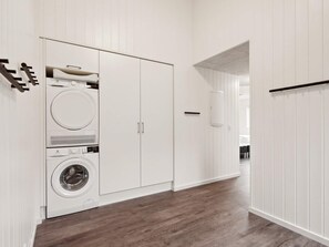 A laundry room with a washing machine and dryer, wooden flooring, and white walls. - 5 Star Holiday Home in Bogense (Bogense)