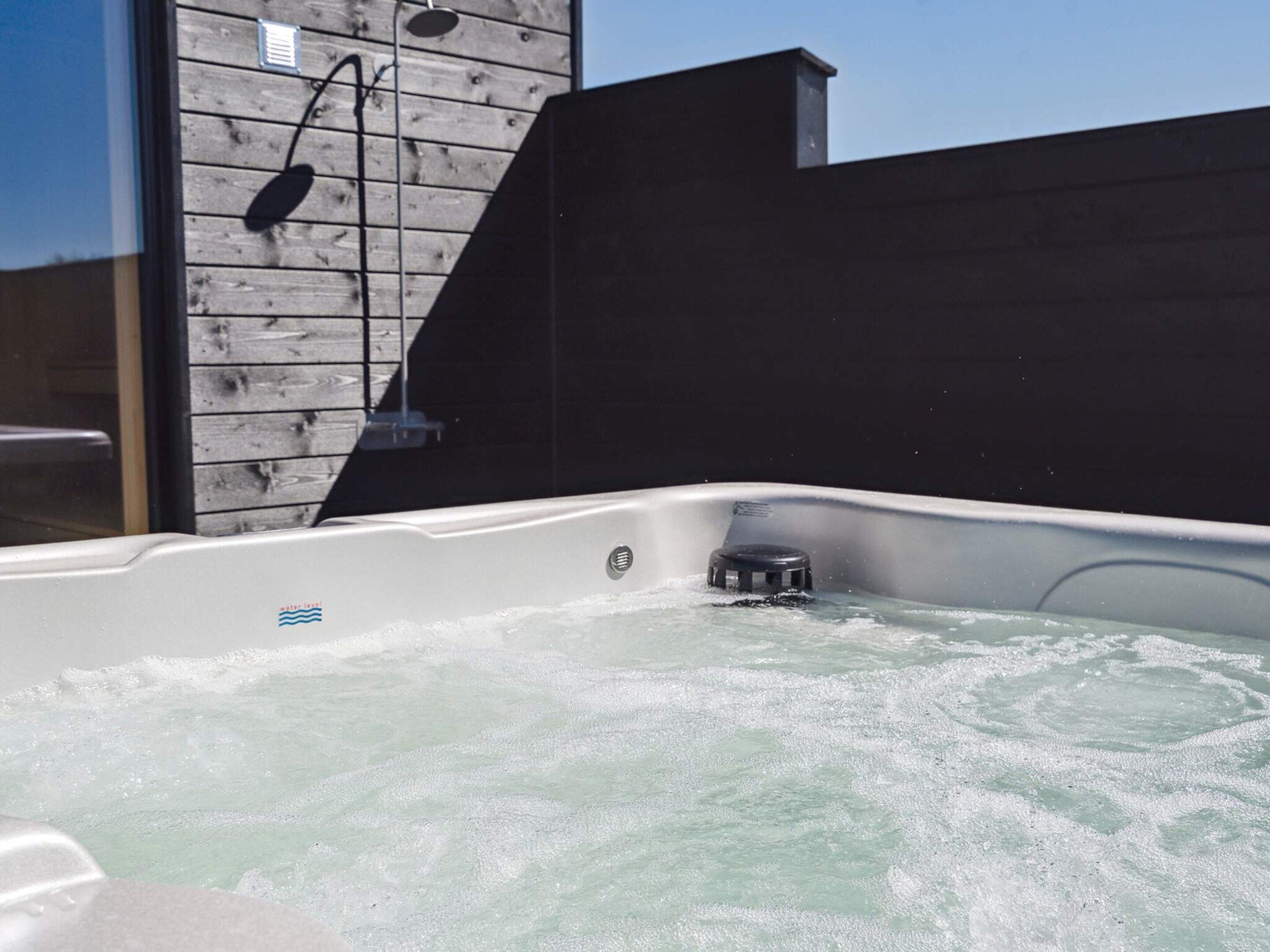 Un bain à remous avec un mur en bois et une structure noire derrière.