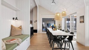 Een moderne eetruimte met een lange tafel, zwarte stoelen en hanglampen.