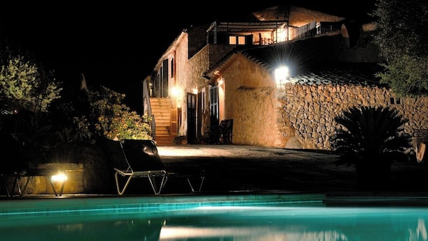 A nighttime view of a house with a swimming pool, stone walls, and outdoor seating. - Agroturismo Sa Vall de son Macia (Manacor)