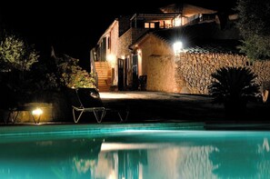 A nighttime view of a house with a swimming pool, stone walls, and outdoor seating. - Agroturismo Sa Vall de son Macia (Manacor)