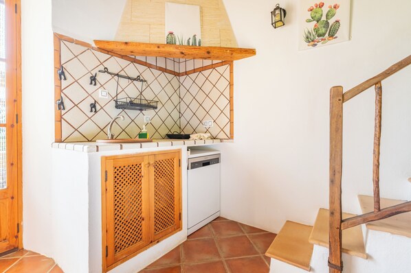 A kitchen with a wooden cabinet, a dishwasher, and a hanging rack. - Agroturismo Sa Vall de son Macia (Manacor)