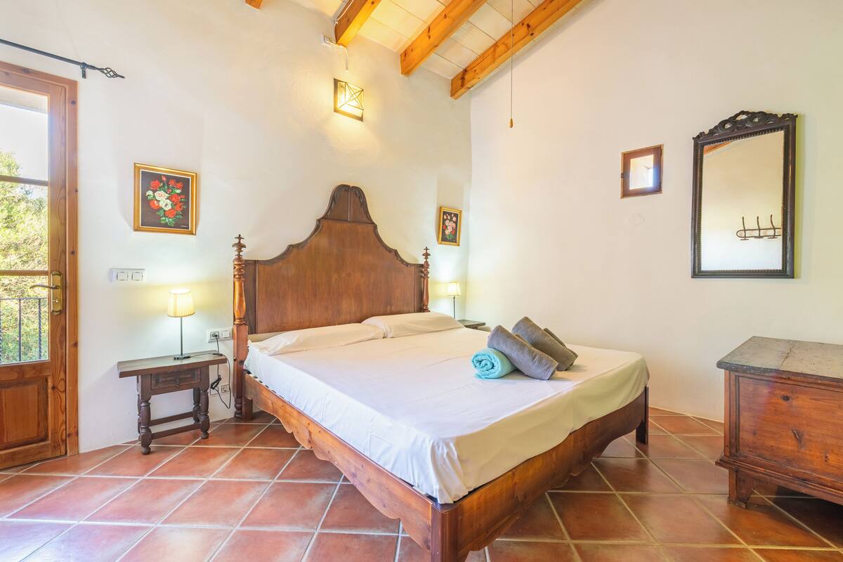 Une chambre à coucher avec un lit en bois, une table de chevet, une commode et un miroir au mur.