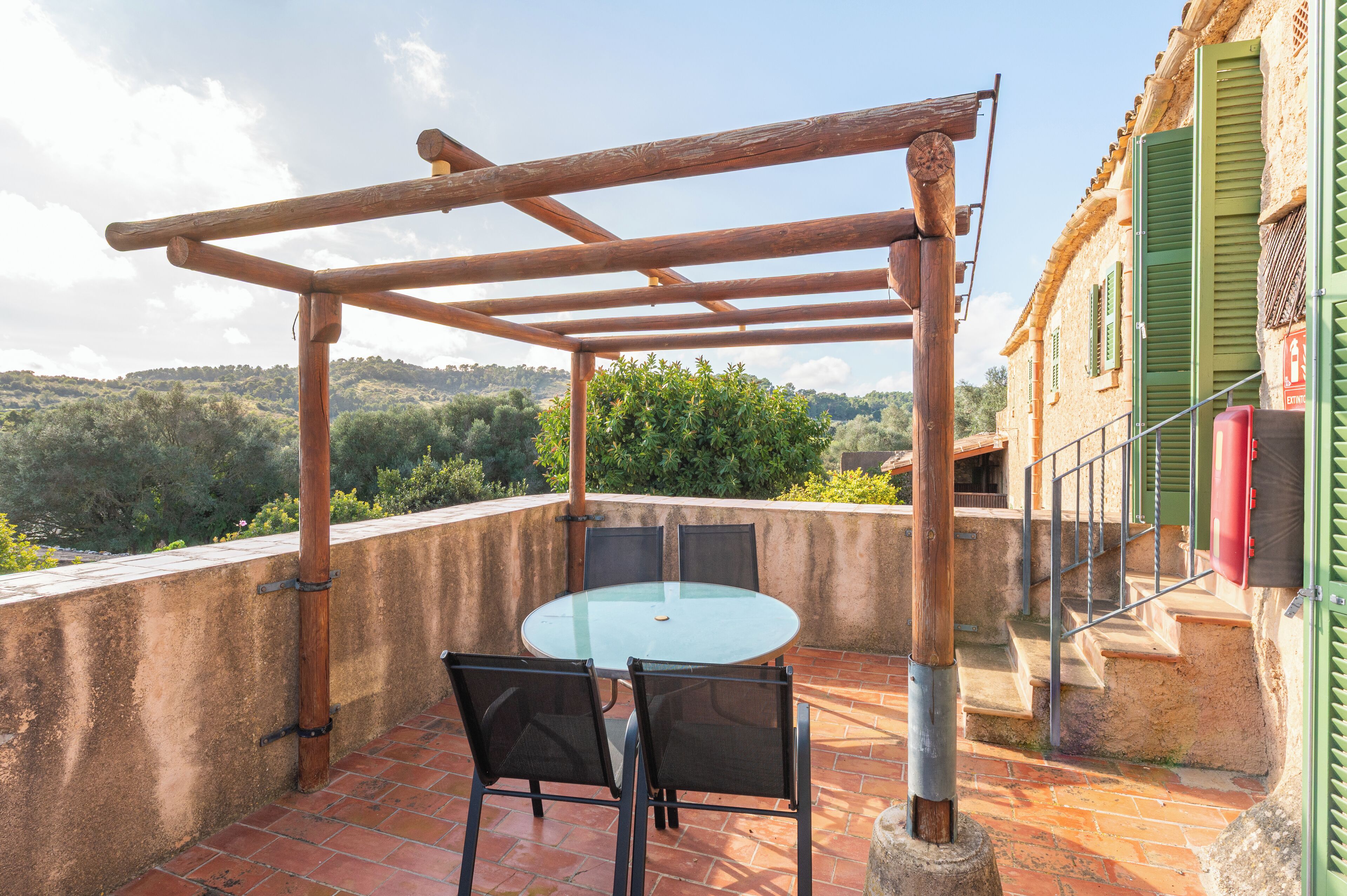Una terraza con un porche de madera, una mesa redonda y sillas.