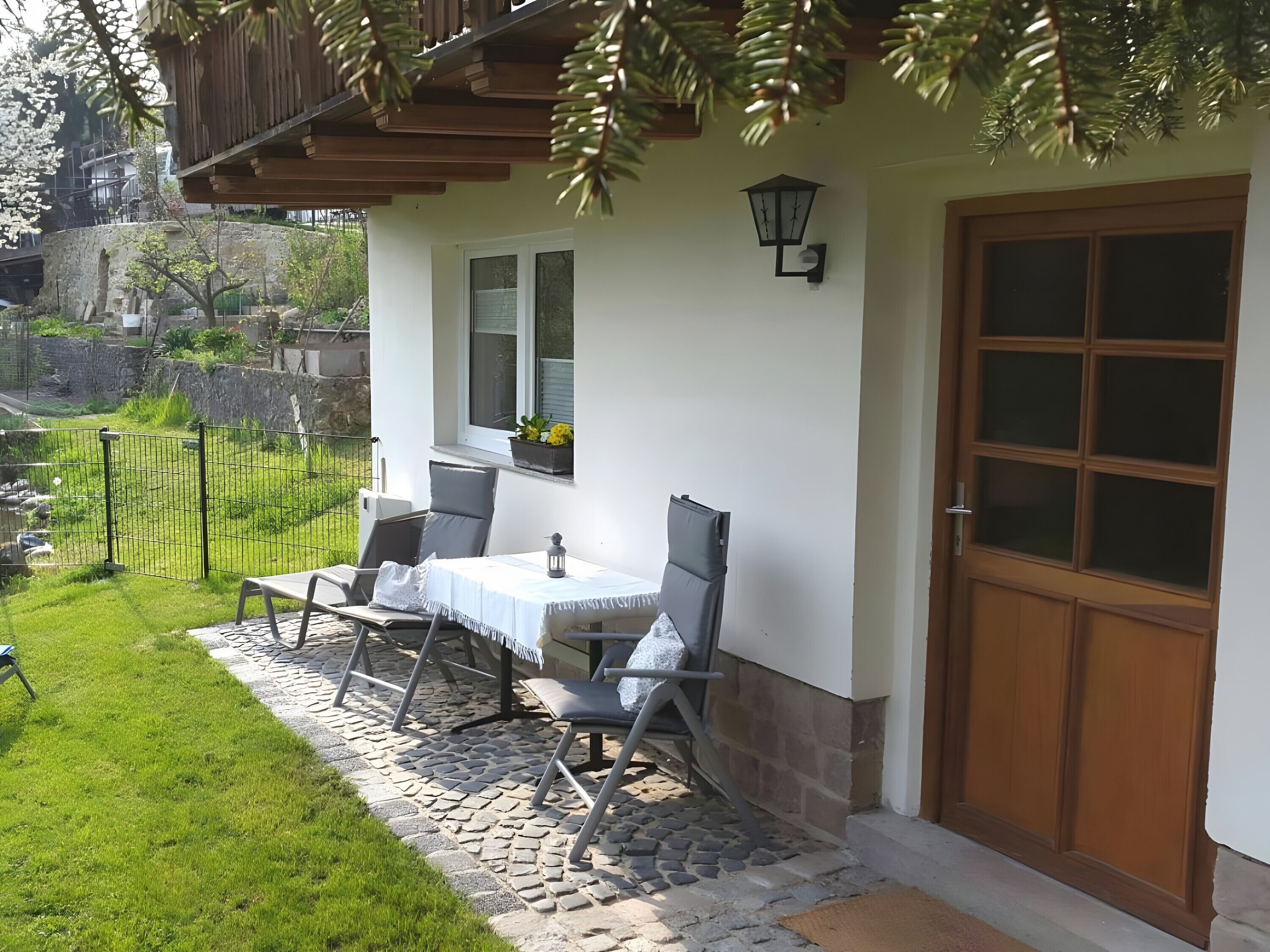 Eine Terrasse mit Tisch und Stühlen, eine Holztür und ein Steinweg.