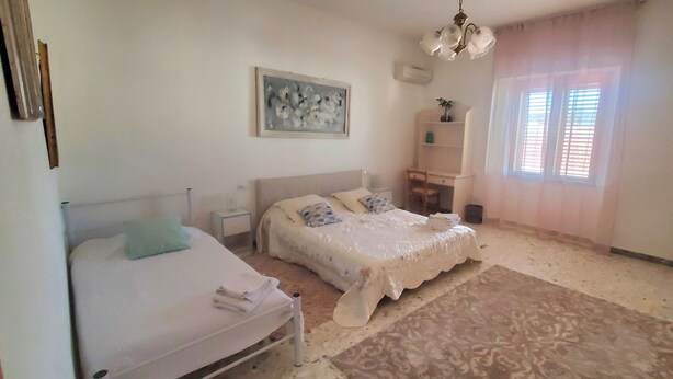 Un dormitorio con dos camas, un escritorio, una silla, un tapete estampado y un cuadro en la pared.