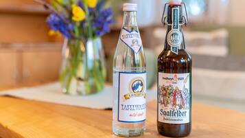 Two bottles of beer on a wooden surface with a blurred background of a room.