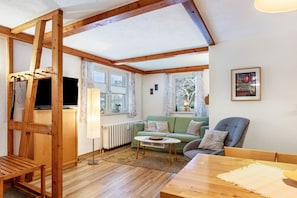 Un salon avec un plafond en bois, un canapé, une table basse et un téléviseur.