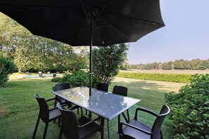 A patio with a glass table and chairs, an umbrella, and a view of a pool and garden. - Charming Cottage in the Périgord Vert Countryside (Angoisse)