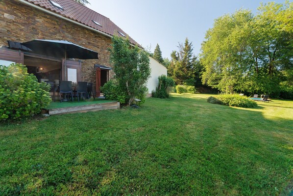 A stone building with a patio area, outdoor seating, and a well-maintained lawn. - Charming Cottage in the Périgord Vert Countryside (Angoisse)