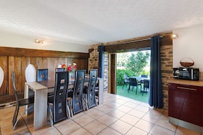 A dining area with a wooden table and chairs, a stone wall, and a view of the outdoors. - Charming Cottage in the Périgord Vert Countryside (Angoisse)