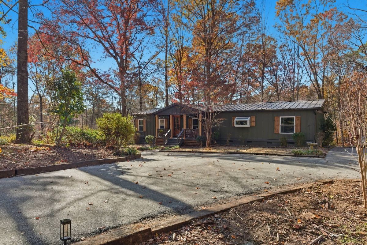 A two-story house with a front porch, surrounded by trees with autumn foliage.
