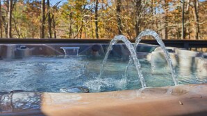 A hot tub with water jets in a natural setting with trees in the background. - NEW Cabin on 3 Acres  W/ Hot Tub+Sauna - Sleeps 8 (Travelers Rest)