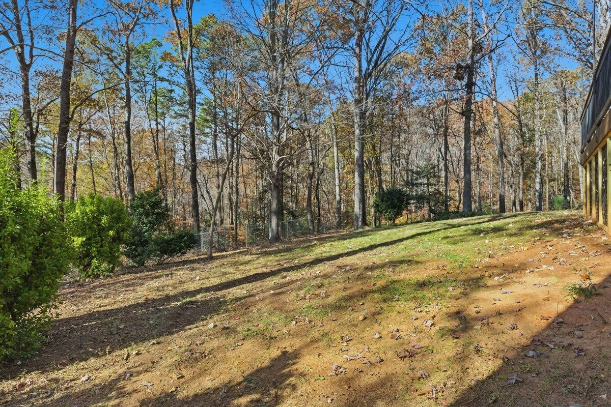 A forested area with a dirt path leading to a building with a sloped roof.
