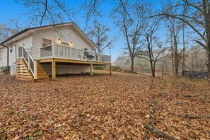 A two-story house with a covered porch and a staircase leading to the upper level. - Cute Cottage, Central Location, Pet Friendly (Greer)
