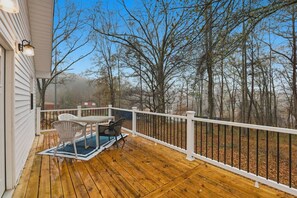 A wooden deck with a white railing, a table, and two chairs. - Cute Cottage, Central Location, Pet Friendly (Greer)