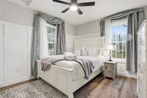 A bedroom with a bed, a nightstand, a lamp, and a window with curtains. - Cute Cottage, Central Location, Pet Friendly (Greer)