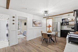 A modern kitchen with a dining area, featuring a central island, built-in appliances, and a contemporary light fixture. - Cute Cottage, Central Location, Pet Friendly (Greer)